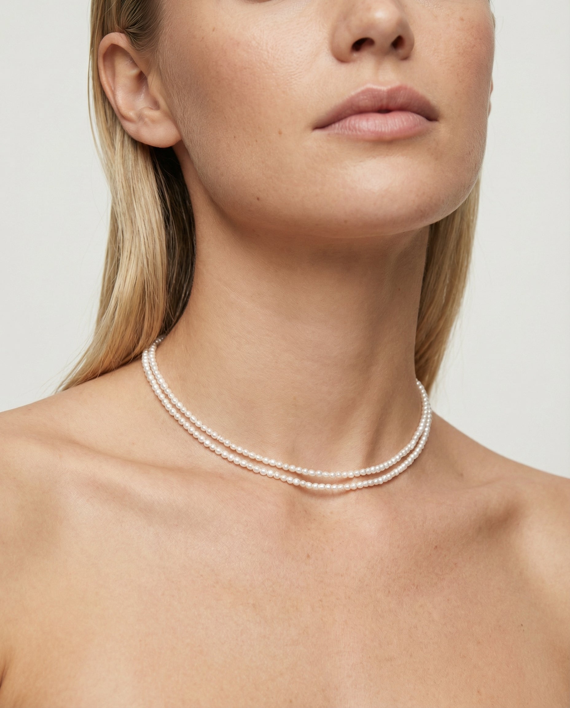 Pearl necklace worn by a model against a neutral background