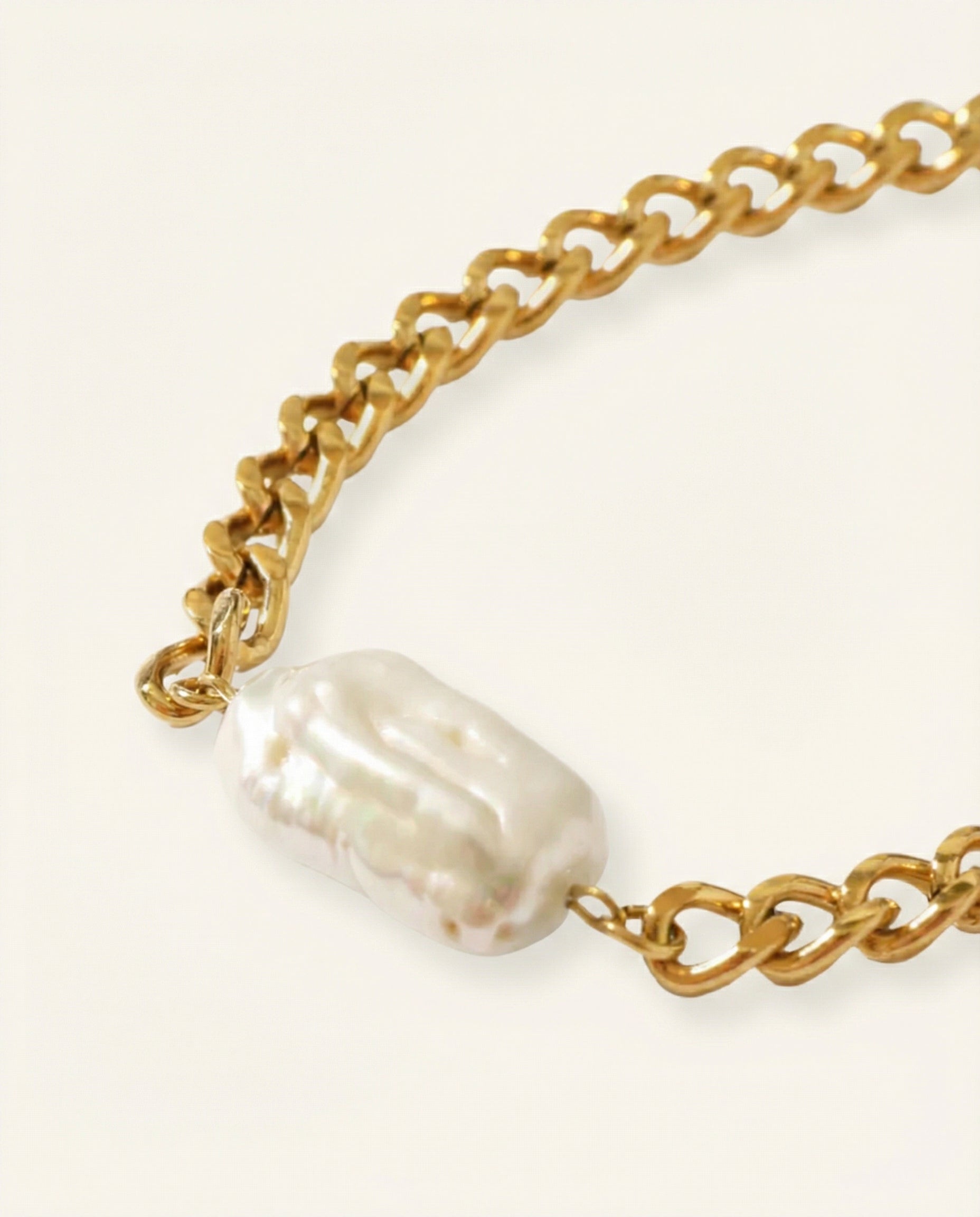 Gold chain necklace with a large pearl pendant on a white background
