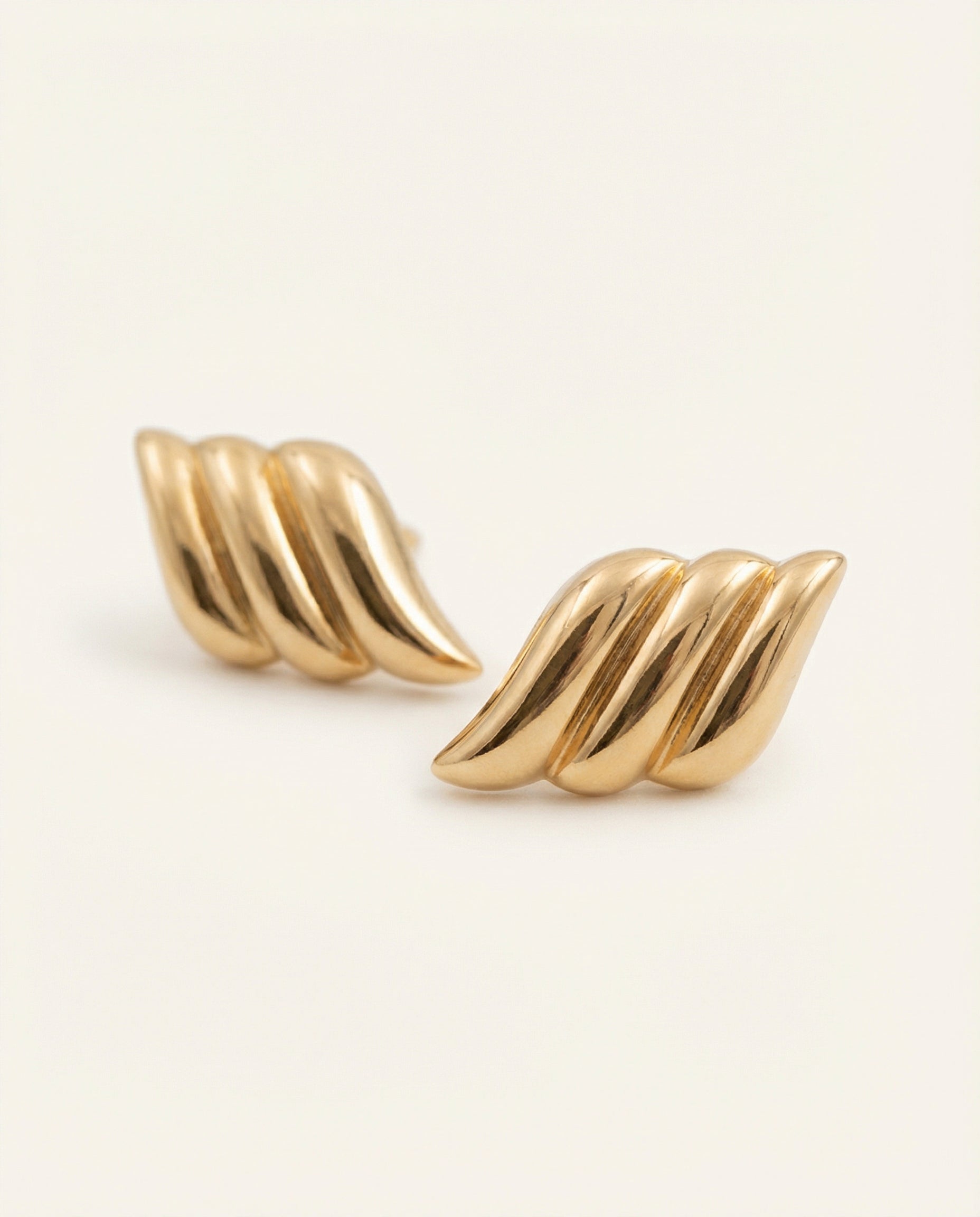 Pair of gold earrings on a light beige background