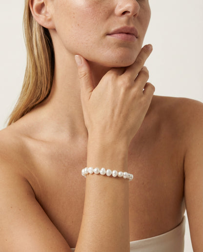 Woman wearing pearl bracelet in studio setting.