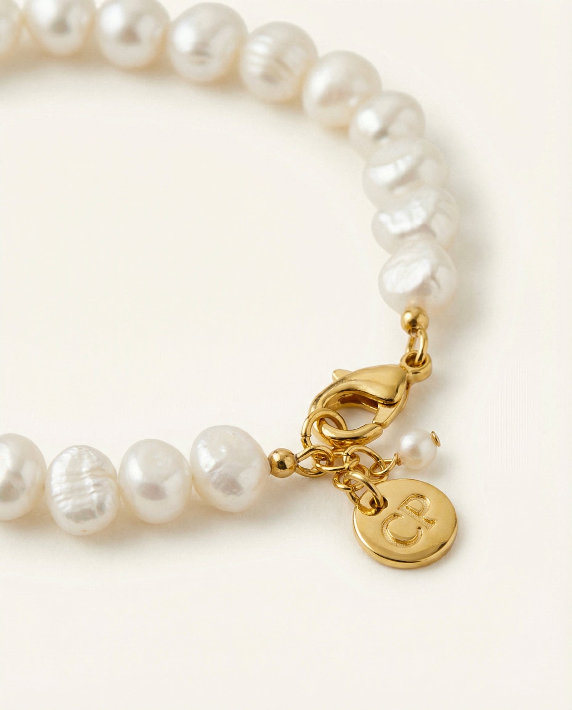 Detail shot of pearl bracelet on beige background.