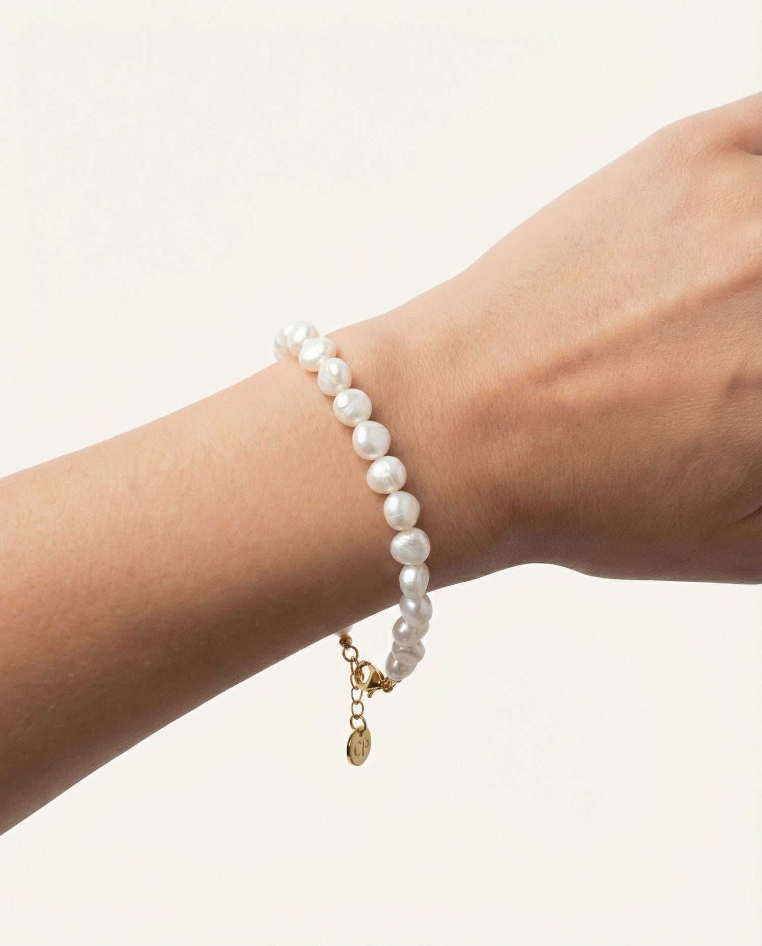 Wrist with pearl bracelet in studio setting.