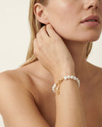 Woman wearing pearl bracelet in studio setting.