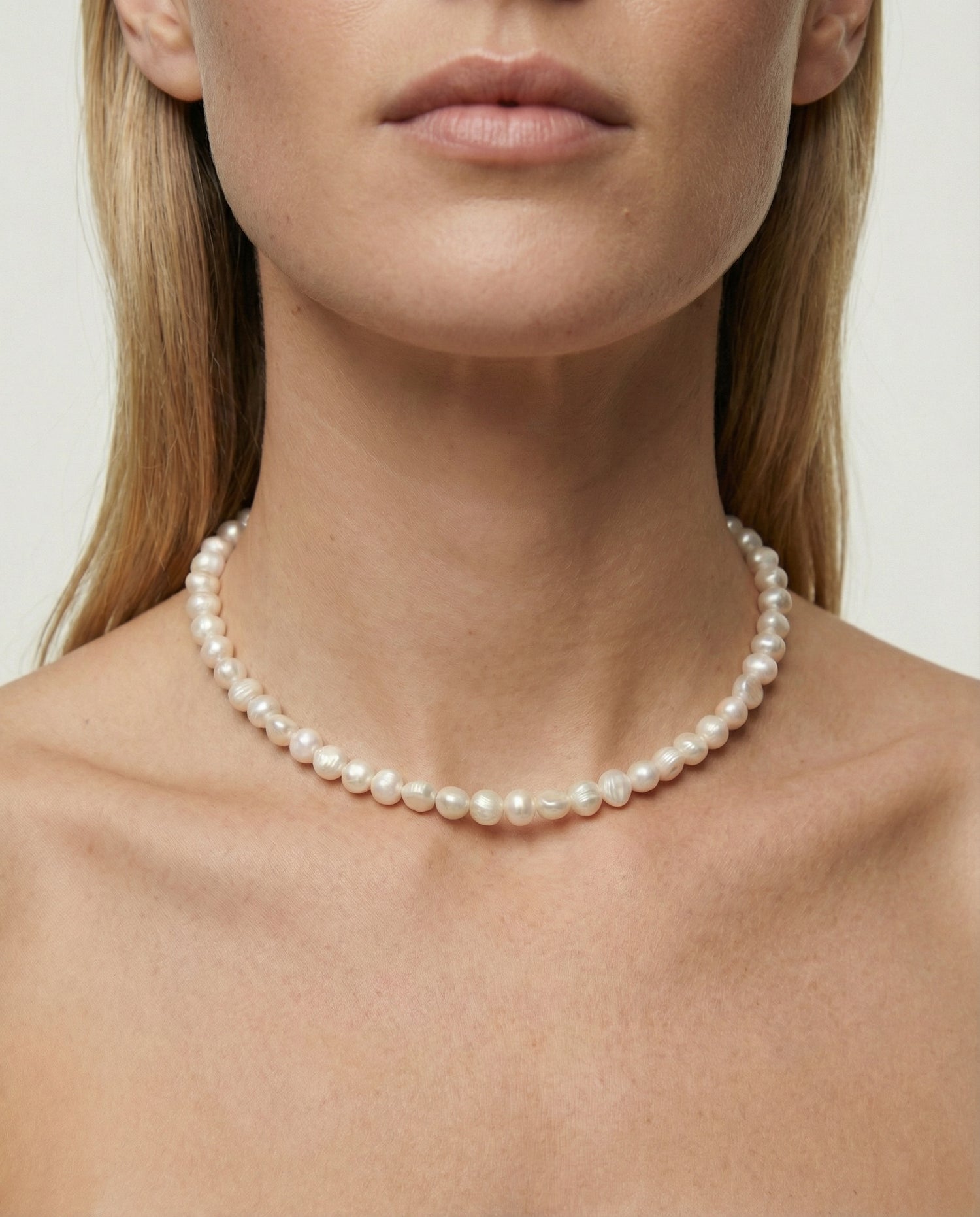 Pearl necklace worn by a model on a plain background