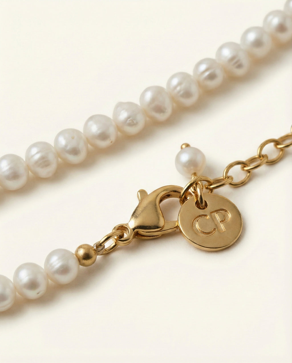 Pearl necklace with a gold clasp featuring initials on a light background