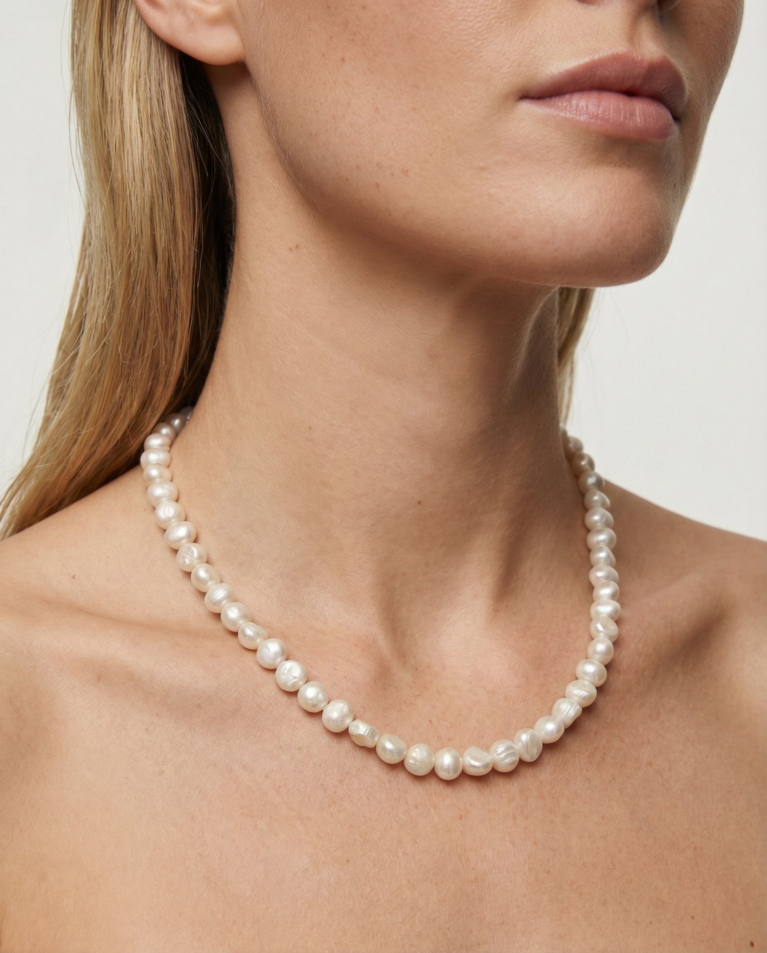 Pearl necklace worn by a model against a neutral background
