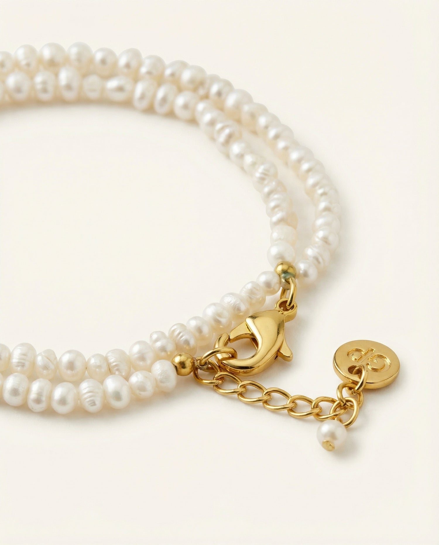 Detail shot of pearl bracelet on beige background.