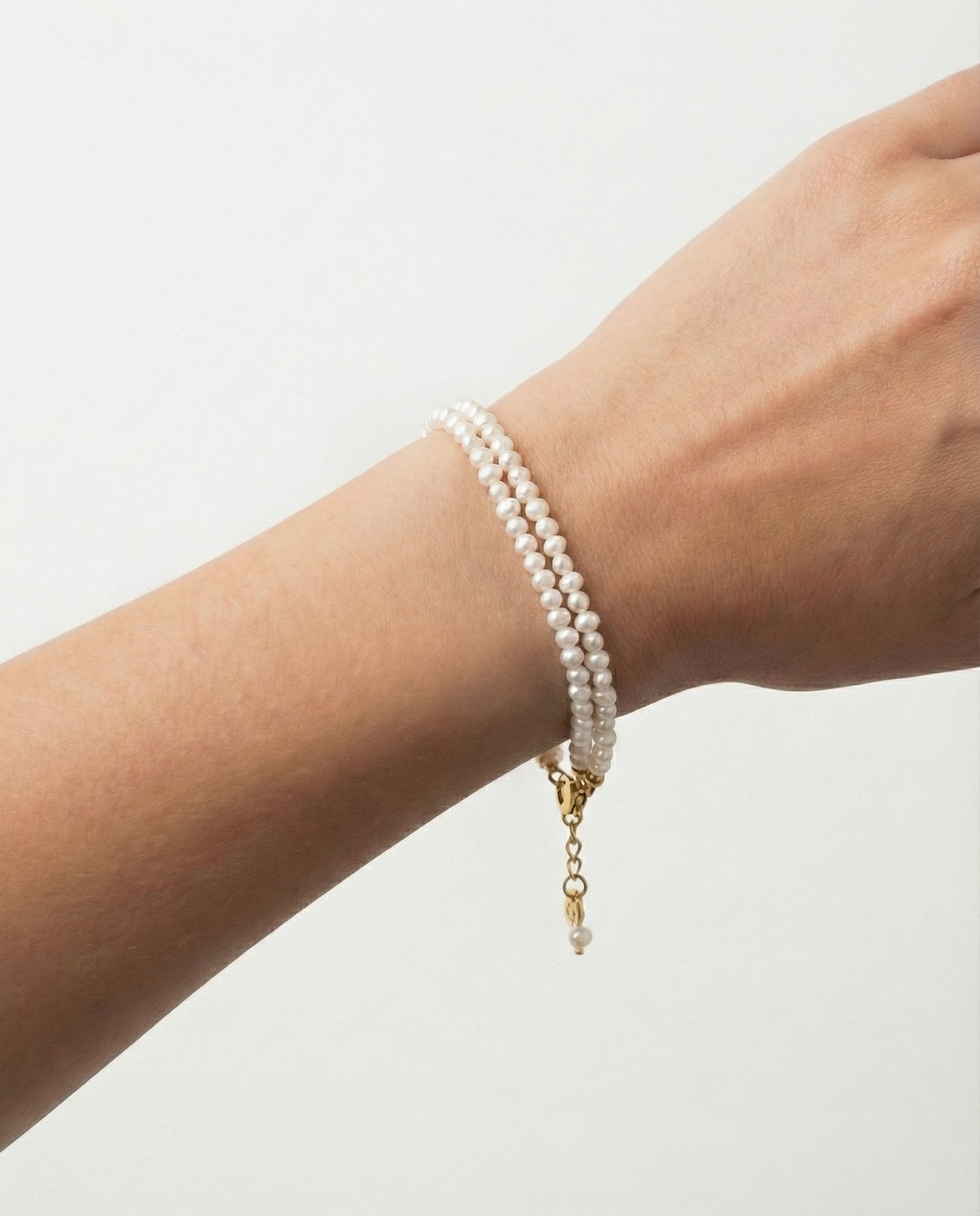 Wrist with pearl bracelet in studio setting.