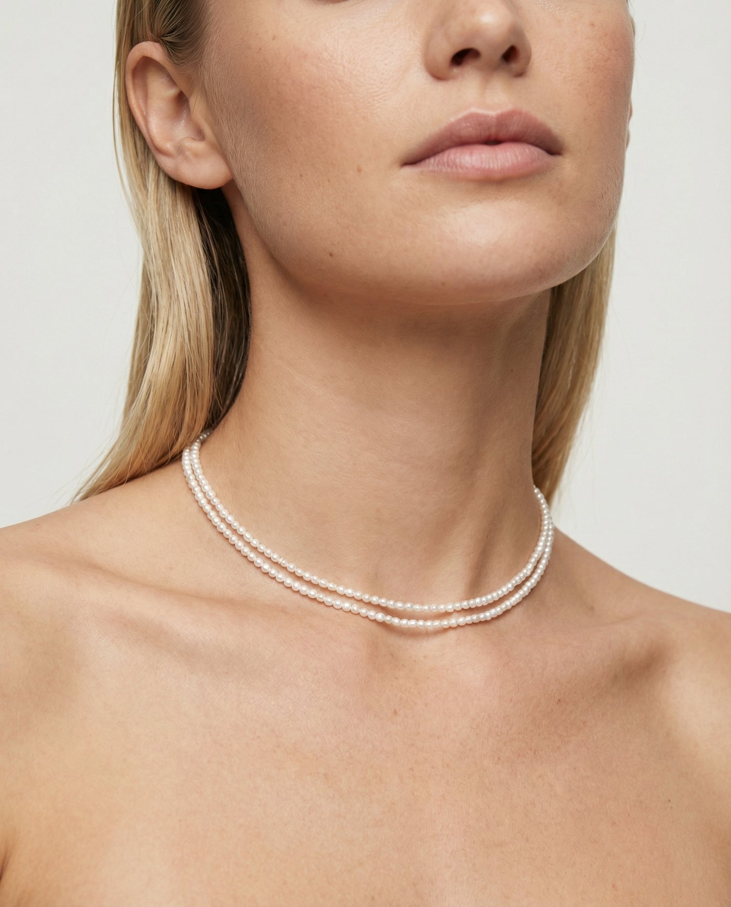 Pearl necklace worn by a model against a neutral background
