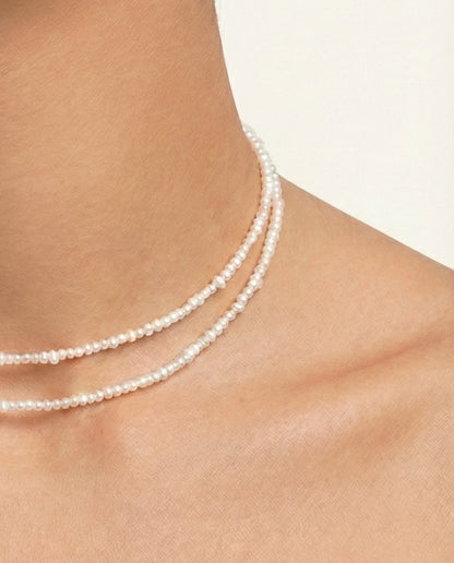 Woman wearing a pearl necklace against a neutral background