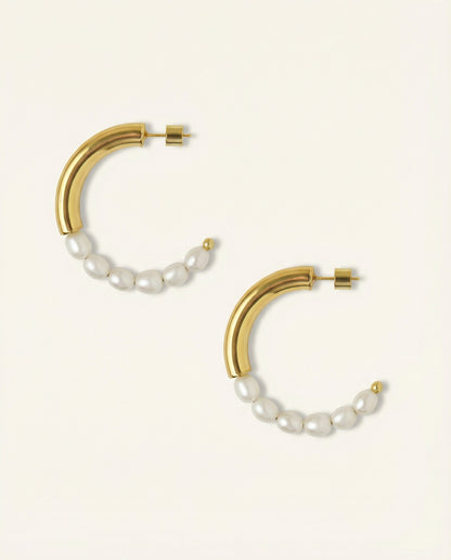 Gold hoop earrings with pearl accents on a light beige background