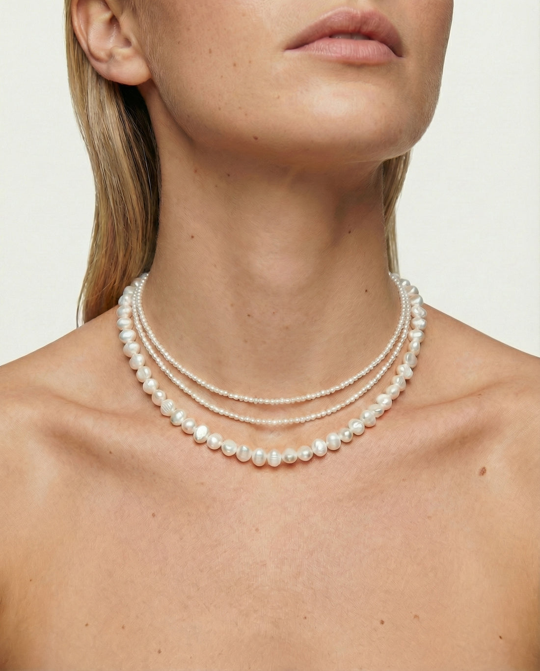 Woman wearing a pearl necklace against a neutral background