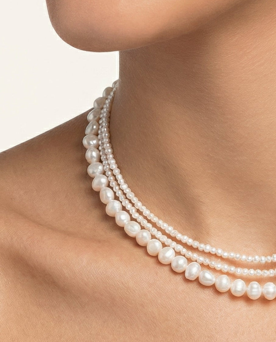 Pearl necklace on a person against a neutral background