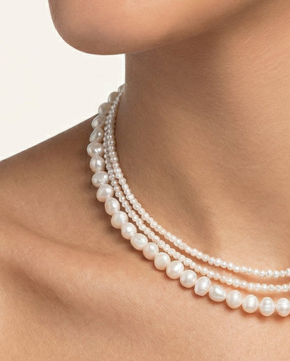 Pearl necklace on a person against a neutral background