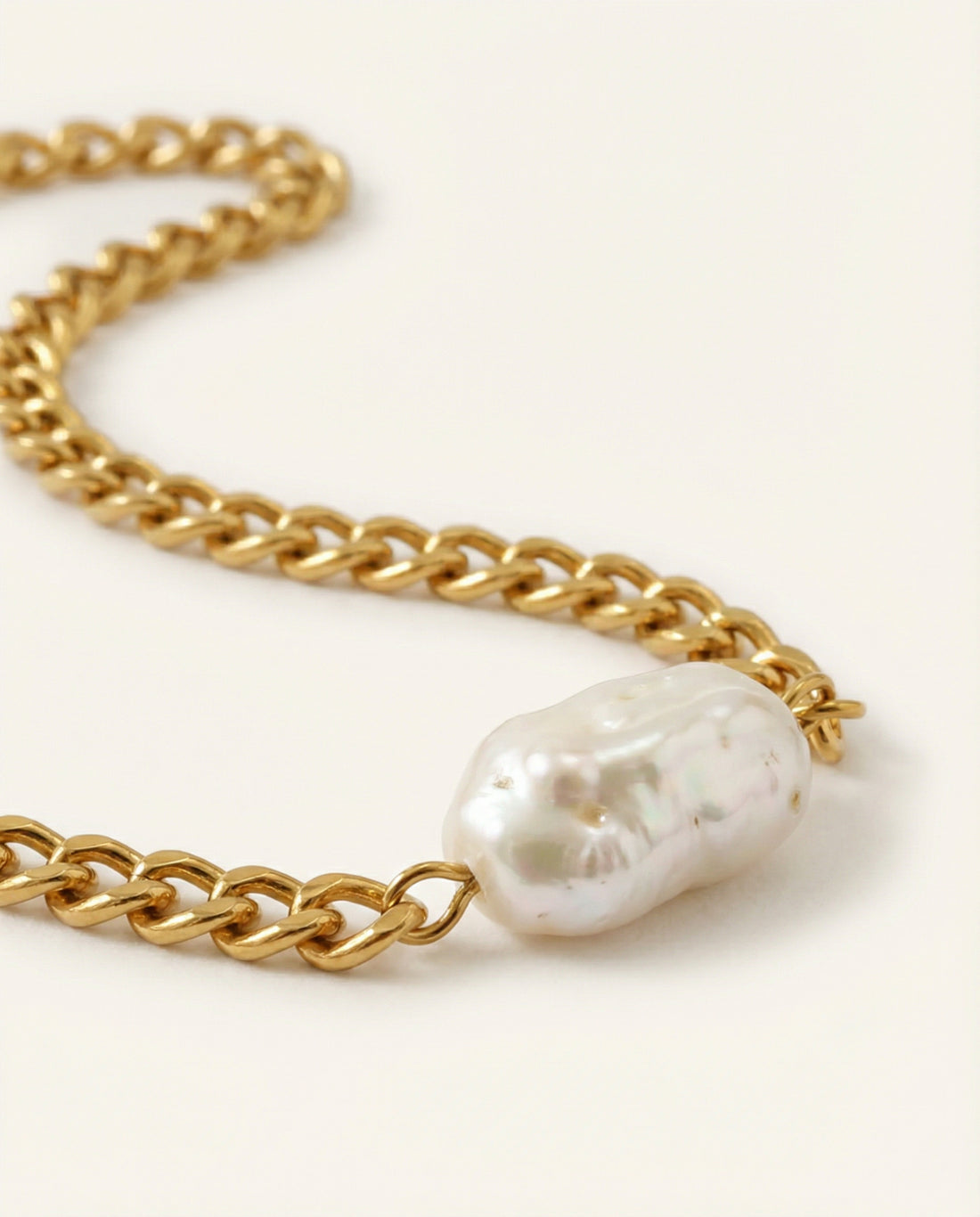 Gold chain necklace with a large pearl pendant on a white background
