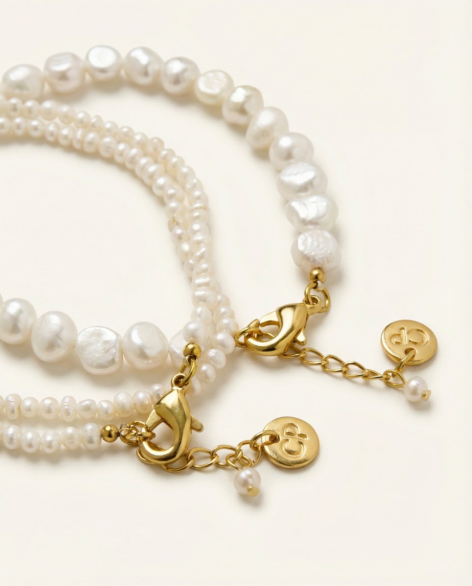 Pearl bracelet with gold charms on a white background