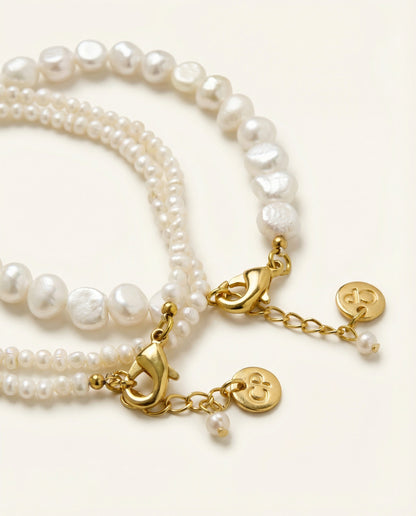 Pearl bracelet with gold charms on a white background